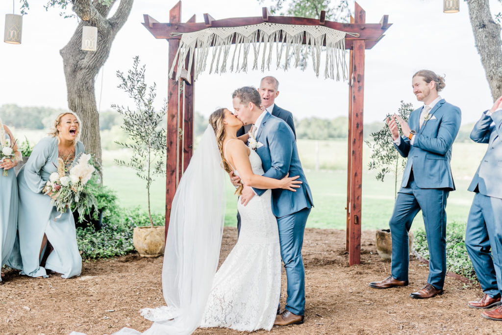 Bride and Groom Ceremony First Kiss Lace Dress Navy Suit | Stonehouse Villa in Driftwood TX by DFW Dallas Fort Worth wedding photographer Karina Danielle Photography