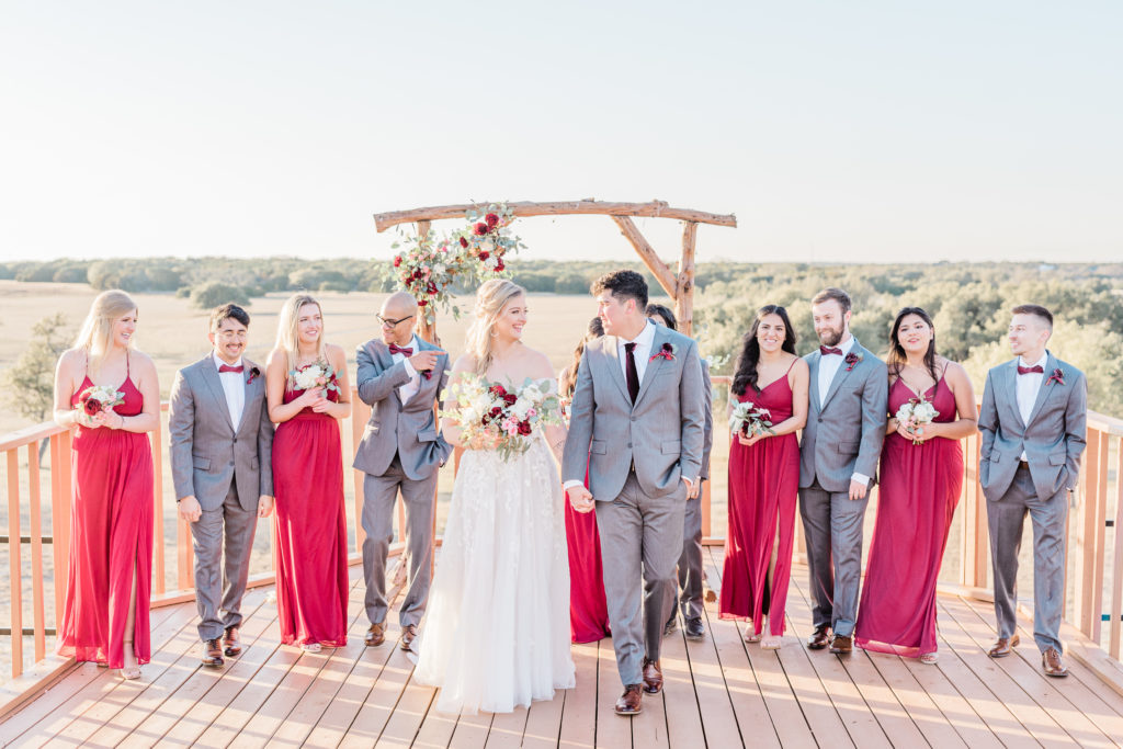 Bridal Party Portrait Red Dresses Grey Suit Velvet Tie Blush and Wine Bouquet Eucalyptus | Wagon Springs Ranch in Burnet TX by DFW Dallas Fort Worth wedding photographer Karina Danielle Photography