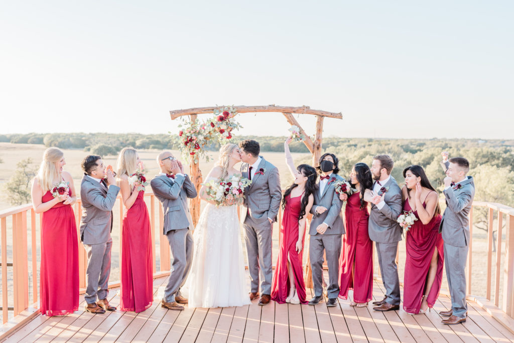 Bridal Party Portrait Red Dresses Grey Suit Velvet Tie Blush and Wine Bouquet Eucalyptus | Wagon Springs Ranch in Burnet TX by DFW Dallas Fort Worth wedding photographer Karina Danielle Photography