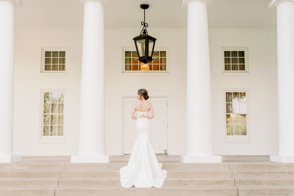 Bridal portrait of bride in timeless, modern satin gown on steps of Arlington Hall venue for Dallas Wedding.