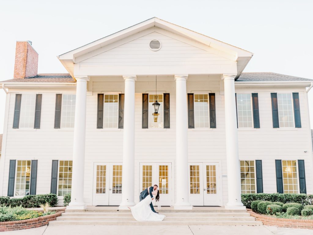 Bride and groom dip and kiss at The Milestone Mansion in Denton, one of Dallas' best wedding venues.