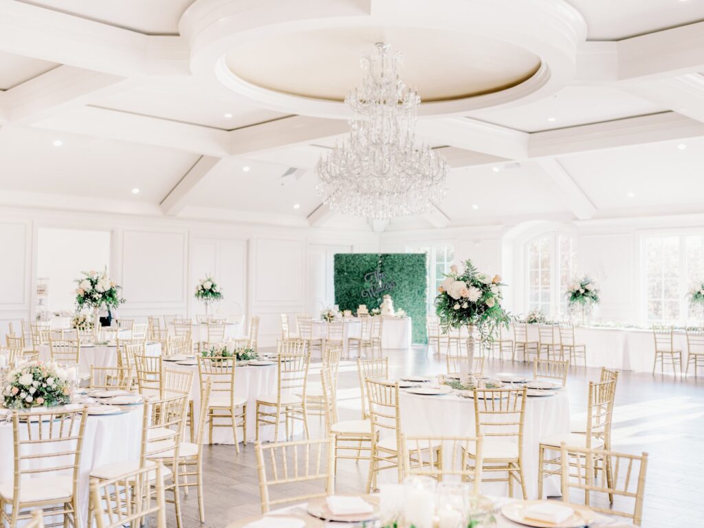 The Hillside Estate wedding reception venue with ivory tablecloths, tall floral arrangements and gold chairs.