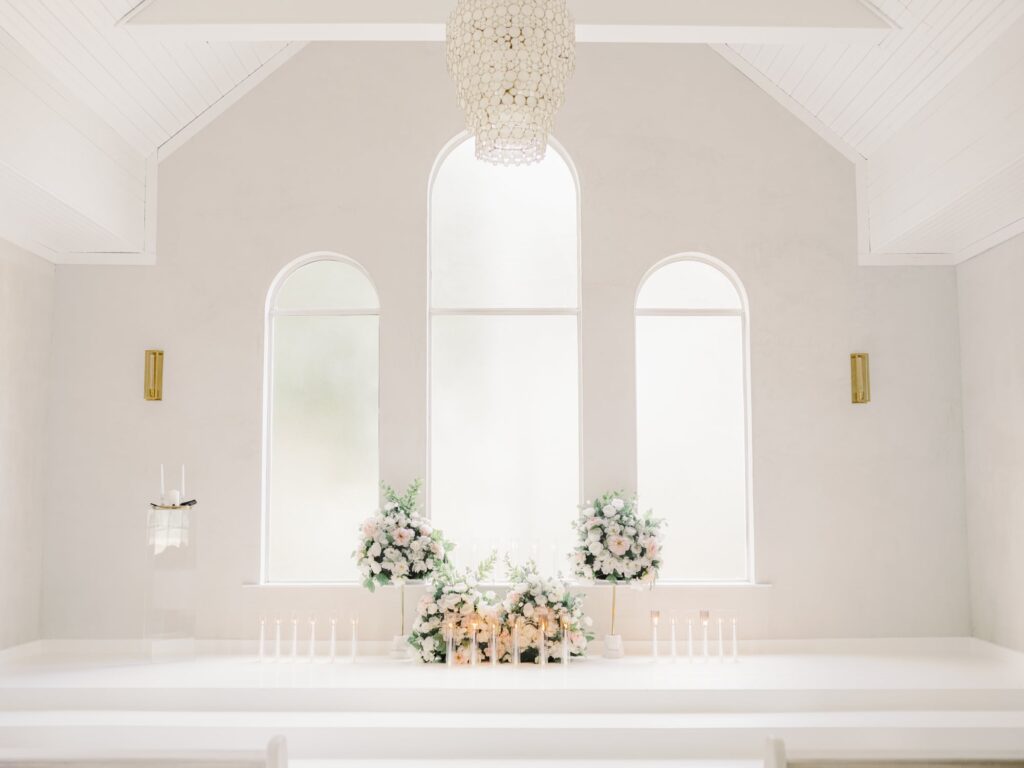 Blush and white roses with candles at the wedding altar of the chapel at the Emerson venue in Dallas.