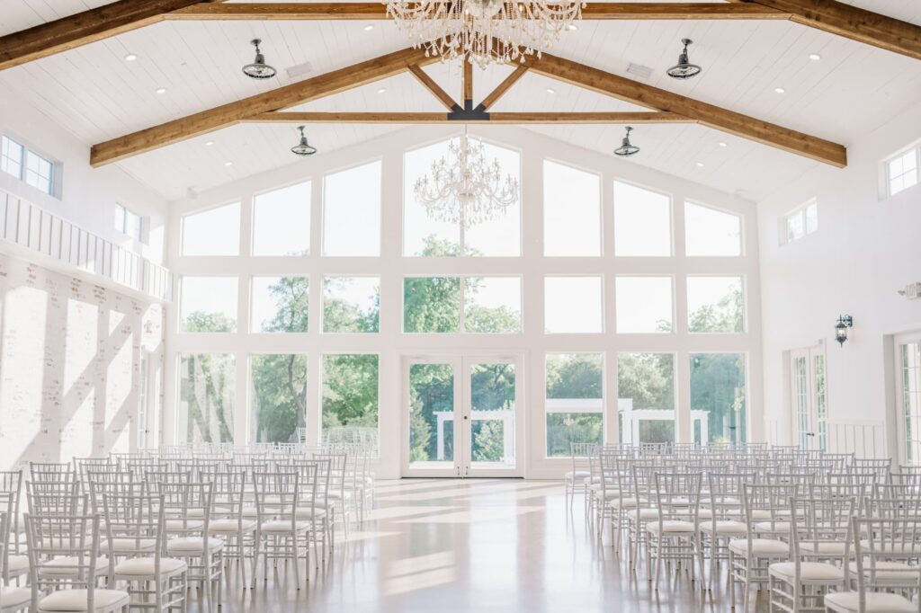 Indoor Dallas wedding venue with tall windows and chandeliers.