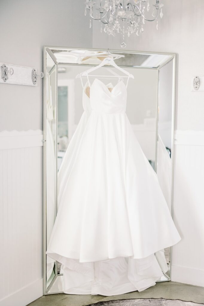 Bride's wedding dress made from satin hanging from mirror in Firefly Garden's bridal suite.