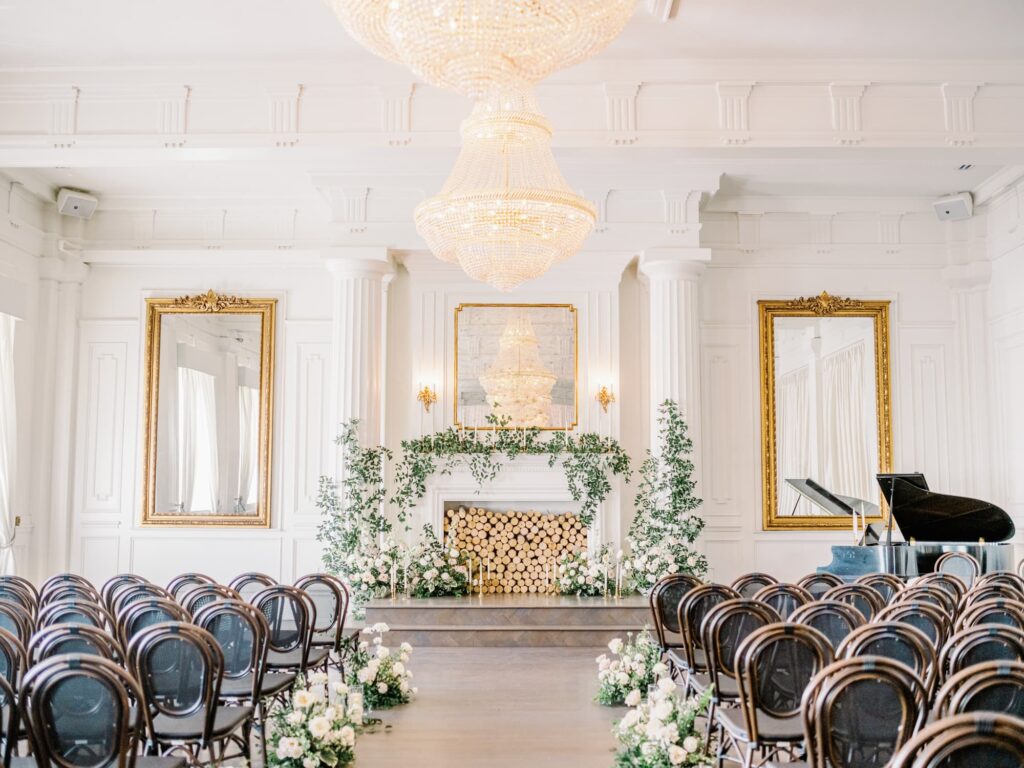 Floral installation with greenery and white roses on the pillars of the fireplace for a wedding at The Mason Dallas venue.