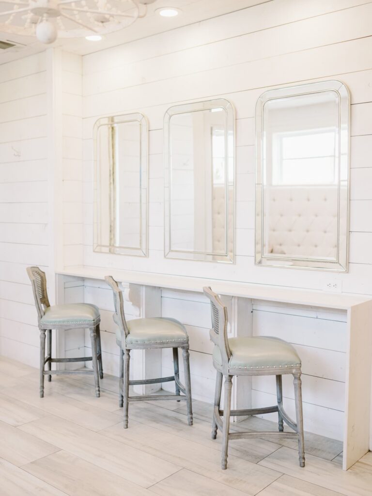 Makeup station at The Nest at Ruth Farms bridal suite with three chairs and large mirrors.