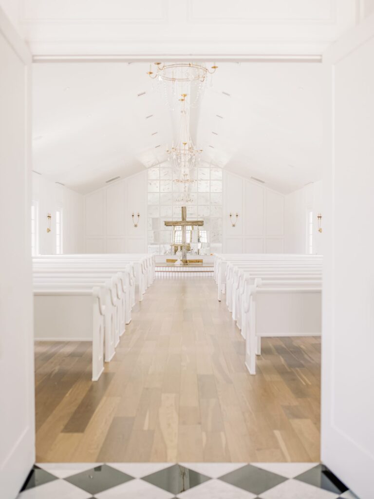 The Nest at Ruth Farms wedding chapel indoors with cross and white pews.